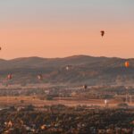 Balony na tle gór i zachodzącego słońca podczas górskich zawodów balonowych w rejonie Krosna
