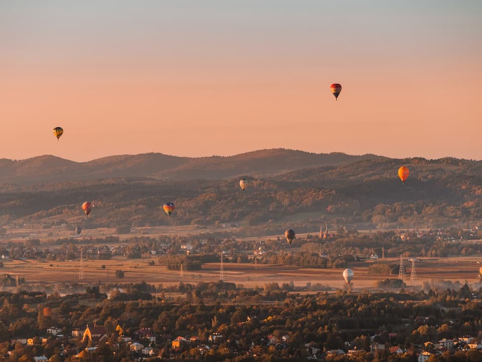Balony na tle gór i zachodzącego słońca podczas górskich zawodów balonowych w rejonie Krosna